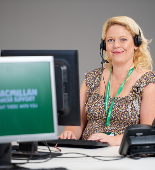 MacMillan call handler sitting at a computer that is displaying the MacMillan logo